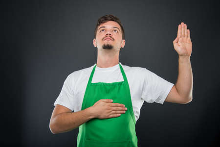 Portrait of attractive supermarket employer making oath gesture on black backgroundの写真素材