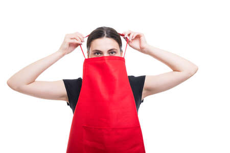 Happy young clerk wearing a red apron at her supermarket job isolated on whiteの写真素材