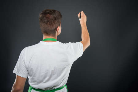 Back view of supermarket employer writing on invisible board on black background with copyspace...