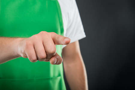 Close-up of supermarket employer pointing camera on black backgroundの写真素材