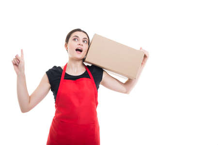 Female seller carrying delivery box in the store and pointing finger up on white background