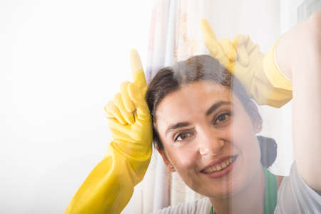 Cheerful cleaning woman acting funny and washing the house windowの写真素材