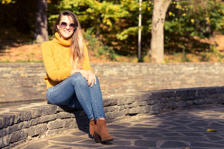 Beautiful stylish girl standing in a park in autumn day with copy spaceの写真素材