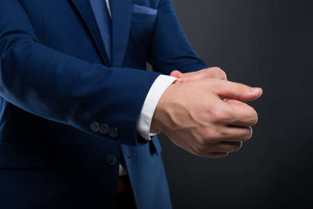 Closeup of elegant young man adjusting his shirt sleeve getting ready for meetingの写真素材
