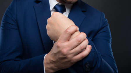 Business man massaging his wrist in closeup view. Pain relief concept