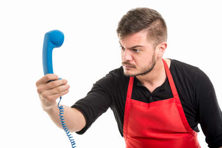 Male supermarket employer looking angry at blue phone receiver isolated on white backgroundの写真素材