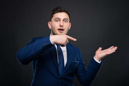 Friendly businessman showing and pointing to something on the palm of his handの写真素材