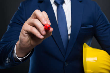 Male architect or constructor with yellow helmet  taking notes on empty screenの写真素材