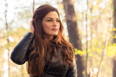 Fashionable woman on autumn background posing in stylish outfitの写真素材