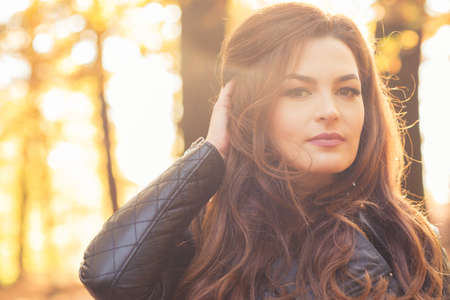 Beautiful fashion girl in sunny autumn forest enjoying nature outsideの写真素材