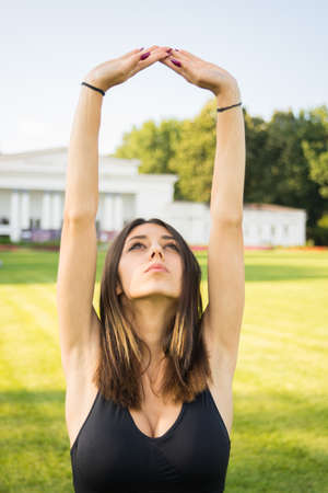 Beautiful woman making stretching exercises and relaxing in the nature