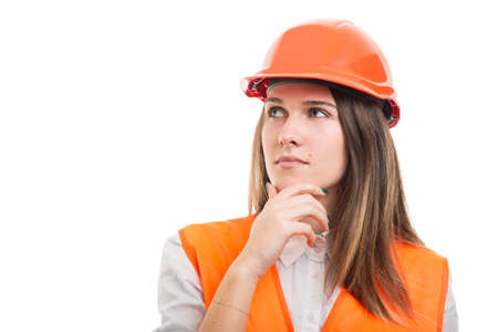 Portrait of pensive female construction or engineer wearing hardhat and looking upの写真素材
