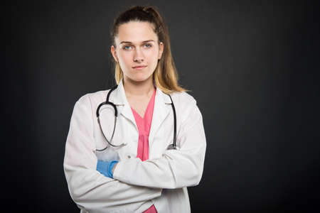 Young doctor portrait  wearing robe standing with arms crossed gesture on black background with copyspace advertising areaの写真素材