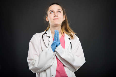 Young doctor portrait  making prayer gesture like hoping concept on black backgroundの写真素材