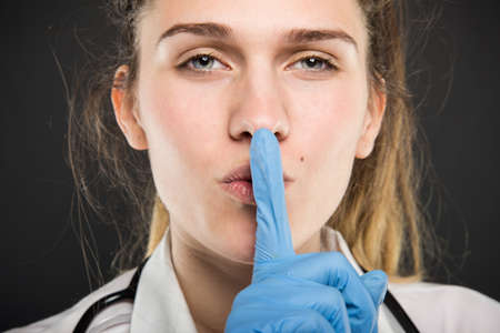 Close-up of young doctor portrait holding making sush gesture on black background
