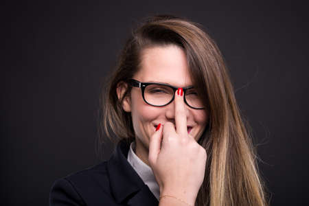 Business woman with glasses doing obscene sign and smiling on black background