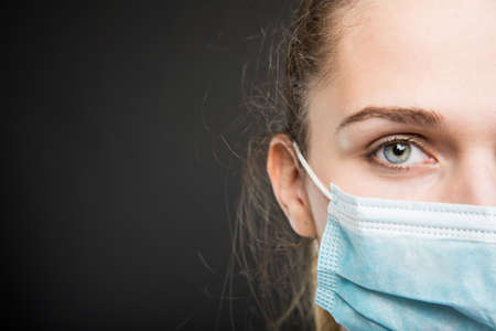 Close-up of half face doctor portrait posing with sterile mark on black background with copyspace advertising areaの写真素材
