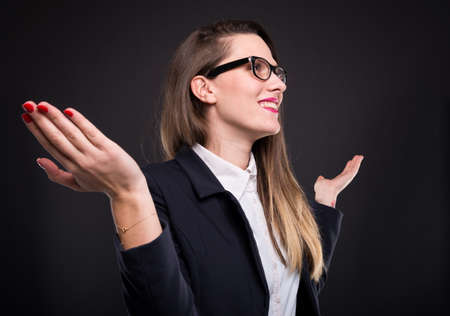 Smiling businesswoman sitting with arms raised after successful business planの写真素材