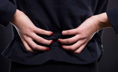 Close-up of  young businesswoman suffers from backache because of wrong position on office deskの写真素材