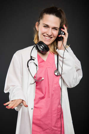 Attractive female doctor wearing headphones acting like a DJ on black backgroundの写真素材