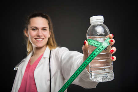 Selective focus of nutritionist holding water and measuring tape on black backgroundの写真素材