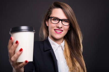 Smiling businesswoman holding take away coffee cup at her officeの写真素材