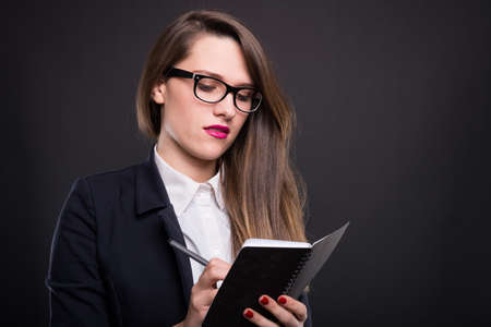Attractive successful woman writing notes in the agenda as work plan or memo conceptの写真素材