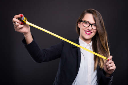 Beautiful young designer holding a yellow roulette with centimeters and millimetersの写真素材