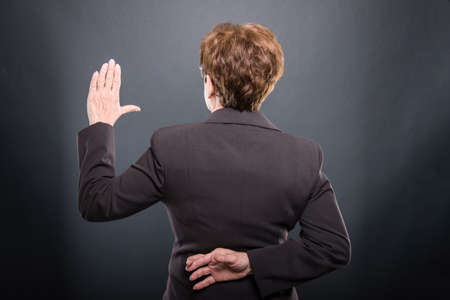 Back view of business senior lady taking fake oath on black backgroundの写真素材
