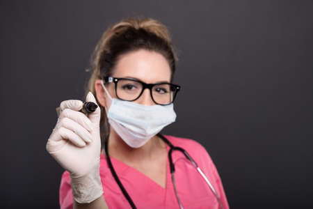 Selective focus of attractive lady doctor writing with marker on black background with copypsace...