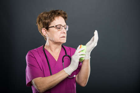 Portrait of senior lady cleaning her gloves with sponge on black background with copyspace advertising areaの写真素材