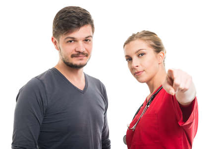 Male patient with female doctor pointing camera isolated on white backgroundの写真素材