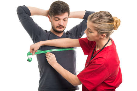 Female doctor measuring male patient body isolated on white backgroundの写真素材