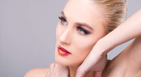 Beautiful young model posing wearing professional make-up on grey background copyspace advertising areaの写真素材