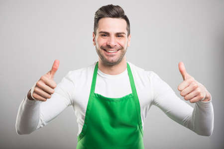 Good looking supermarket employer showing double like or thumb up gesture and smiling on white backgroundの写真素材