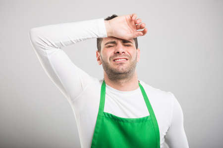 Good looking supermarket employer holding head like hurting on white backgroundの写真素材