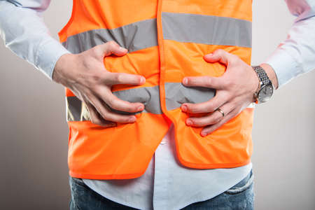 Close-up of architect holding belly like hurting on gray backgroundの写真素材
