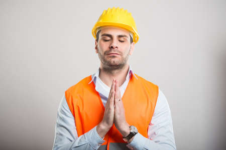 Portrait of young architect holding hands together like praying on gray backgroundの写真素材
