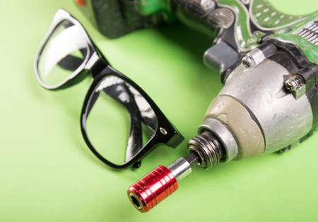 Close-up of drill and one pair of glasses green desk or backgroundの写真素材