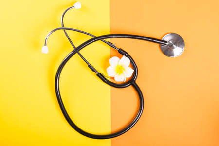 One stethoscope and flower on yellow and orange backgroundの写真素材