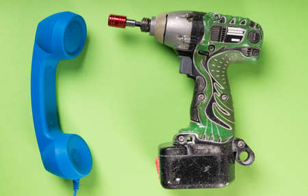 Close-up of drill and big blue telephone receiver on green desk or backgroundの写真素材