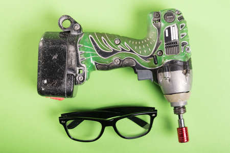 One drill and one pair of glasses on green desk or backgroundの写真素材