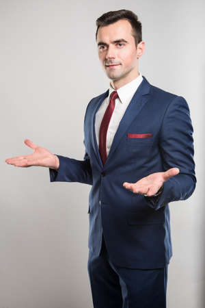 Attractive business man posing gesturing with hands like explaining on gray backgroundの写真素材