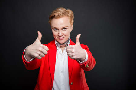 Portrait of attractive business woman showing double like gesture on black background with copyspace advertising areaの写真素材