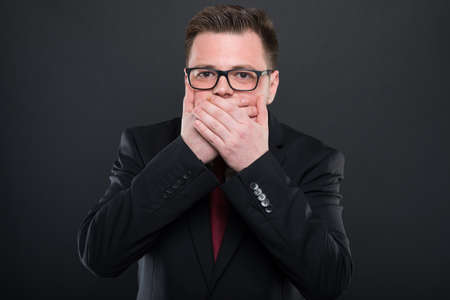 Business man making covering mouth like mute concept on black background
