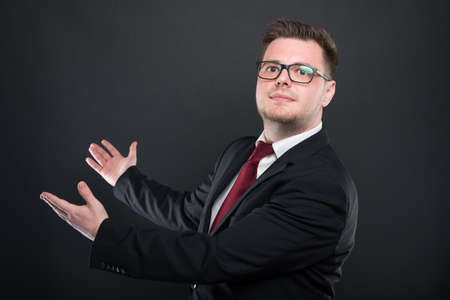 Business man wearing black suit showing copyspace on black background with copy advertising area