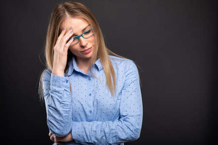 Business lady wearing blue glasses posing like finding solution on black background with copyspace advertising areaの写真素材