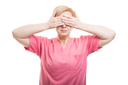 Female nurse wearing pink scrubs covering eyes like blind concept isolated on white backgroundの写真素材