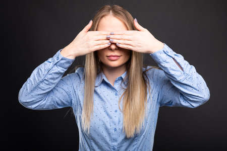 Business lady wearing blue glasses covering eyes like blind gesture on black backgroundの写真素材