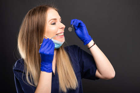 Beautiful female dentist using tools wearing scrubs on black background with copypsace advertising areaの写真素材